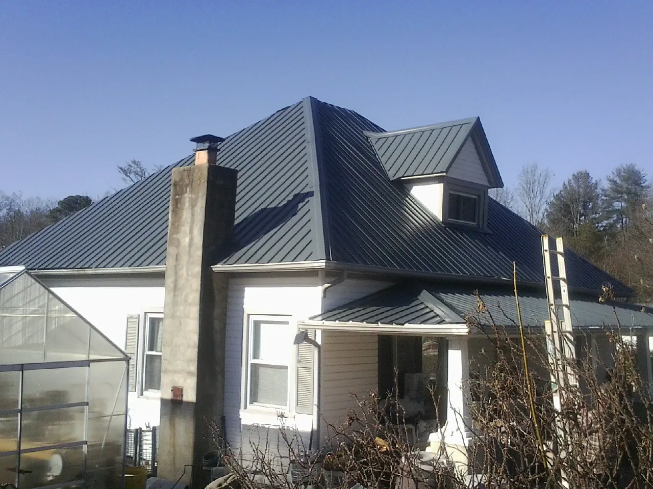 Dark blue standing seam metal roof on a white farmhouse with dormer — Slate & Tile Roof Repair by Roofing Brothers in Big Indian