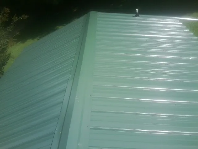 New green metal panels meeting at the ridge of a roof — Flat Roof Repair work by our crew in Big Indian