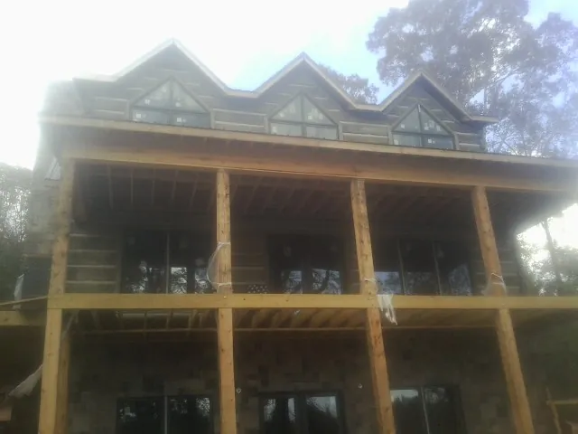 Dormers and porch framing on a large log home under construction — Roof Coating work by our crew in Big Indian