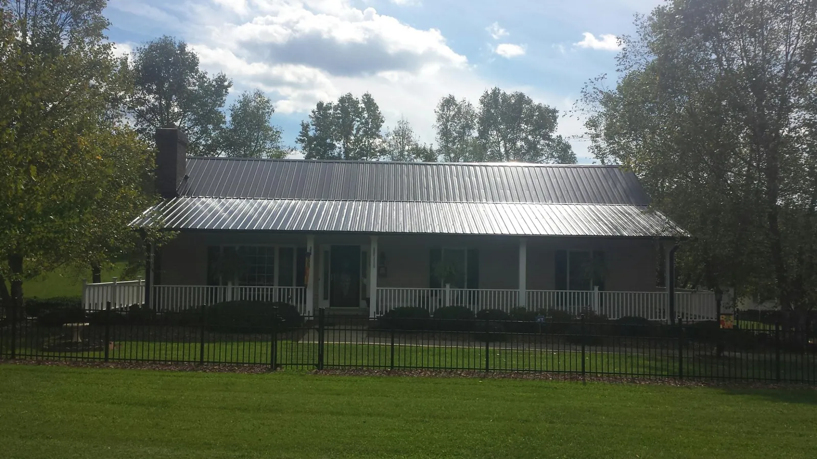 Gray metal roof on a brick ranch with a full width front porch — Gutter Guard Installation work by our crew in Big Indian