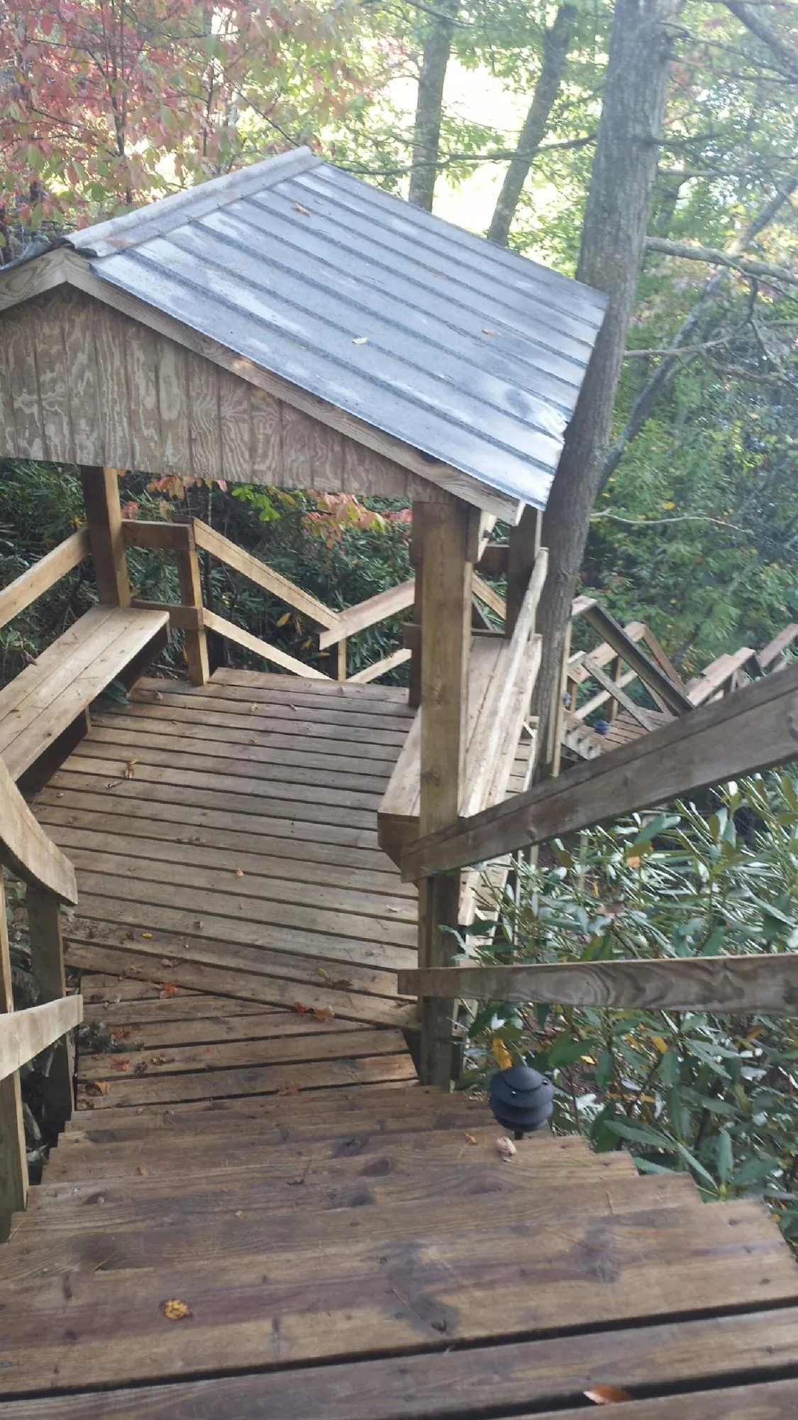 Metal roofed shelter over wooden steps on a wooded walkway — Skylight Repair & Installation work by our crew in Big Indian