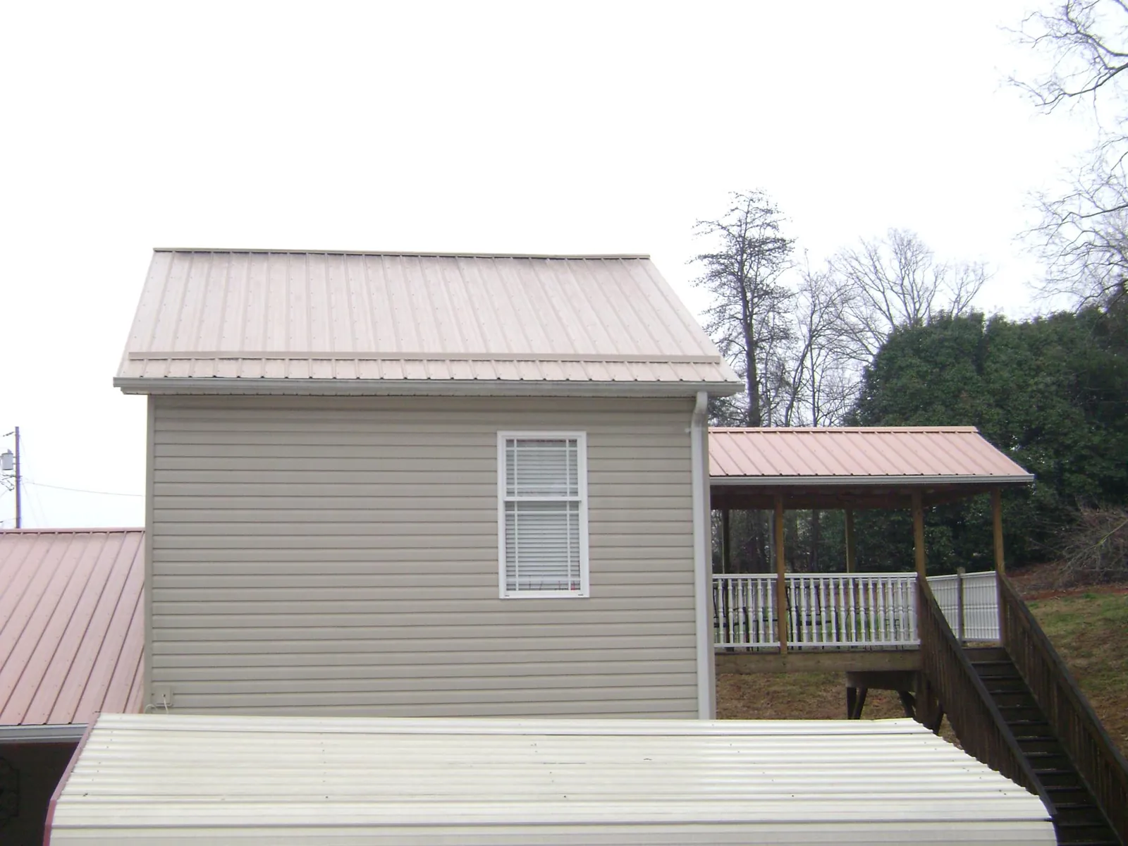 Tan metal roofs on a two story addition and attached porch, from a Roof Replacement job in Big Indian